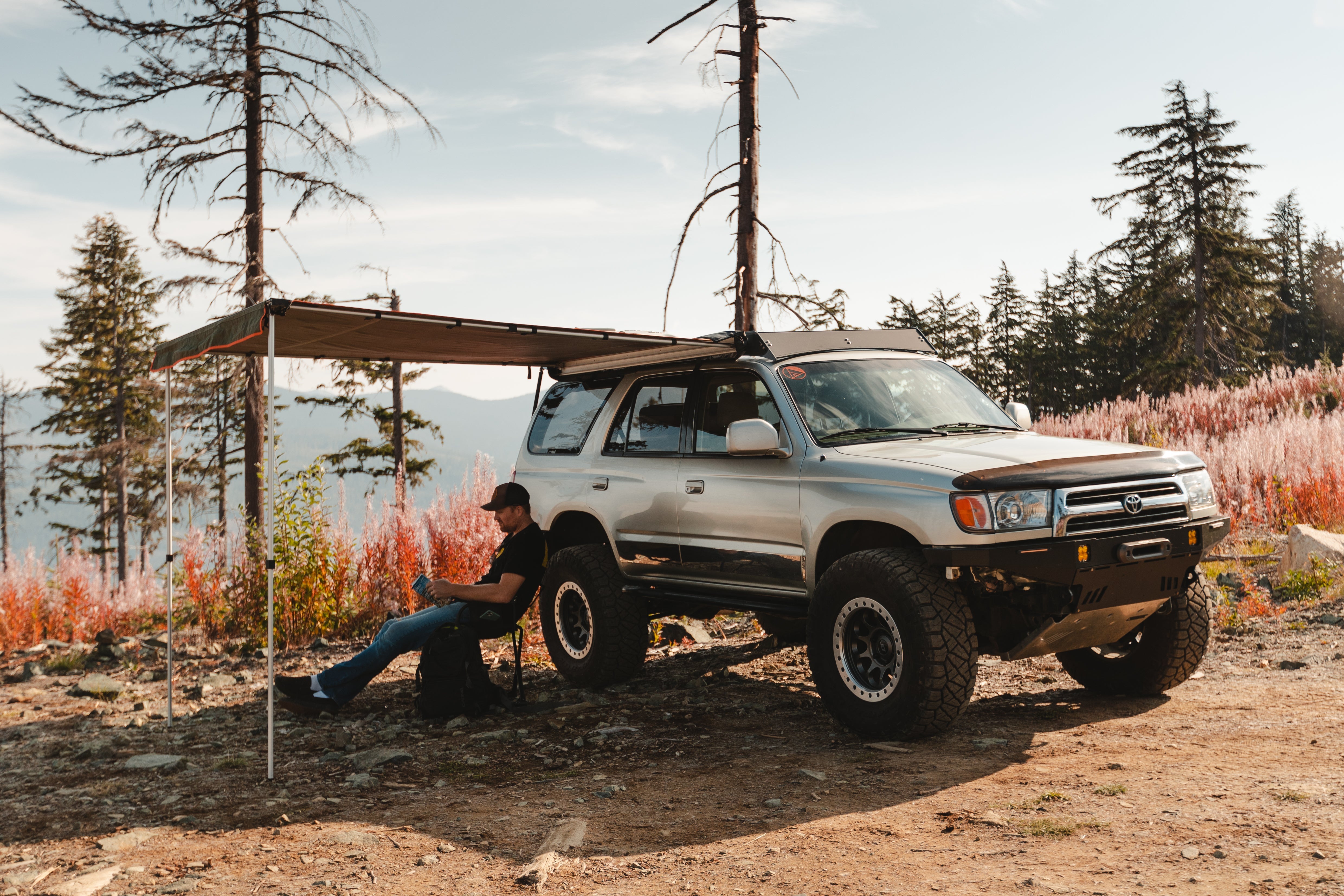 Overlander relaxing under a deployed ROAM rooftop awning