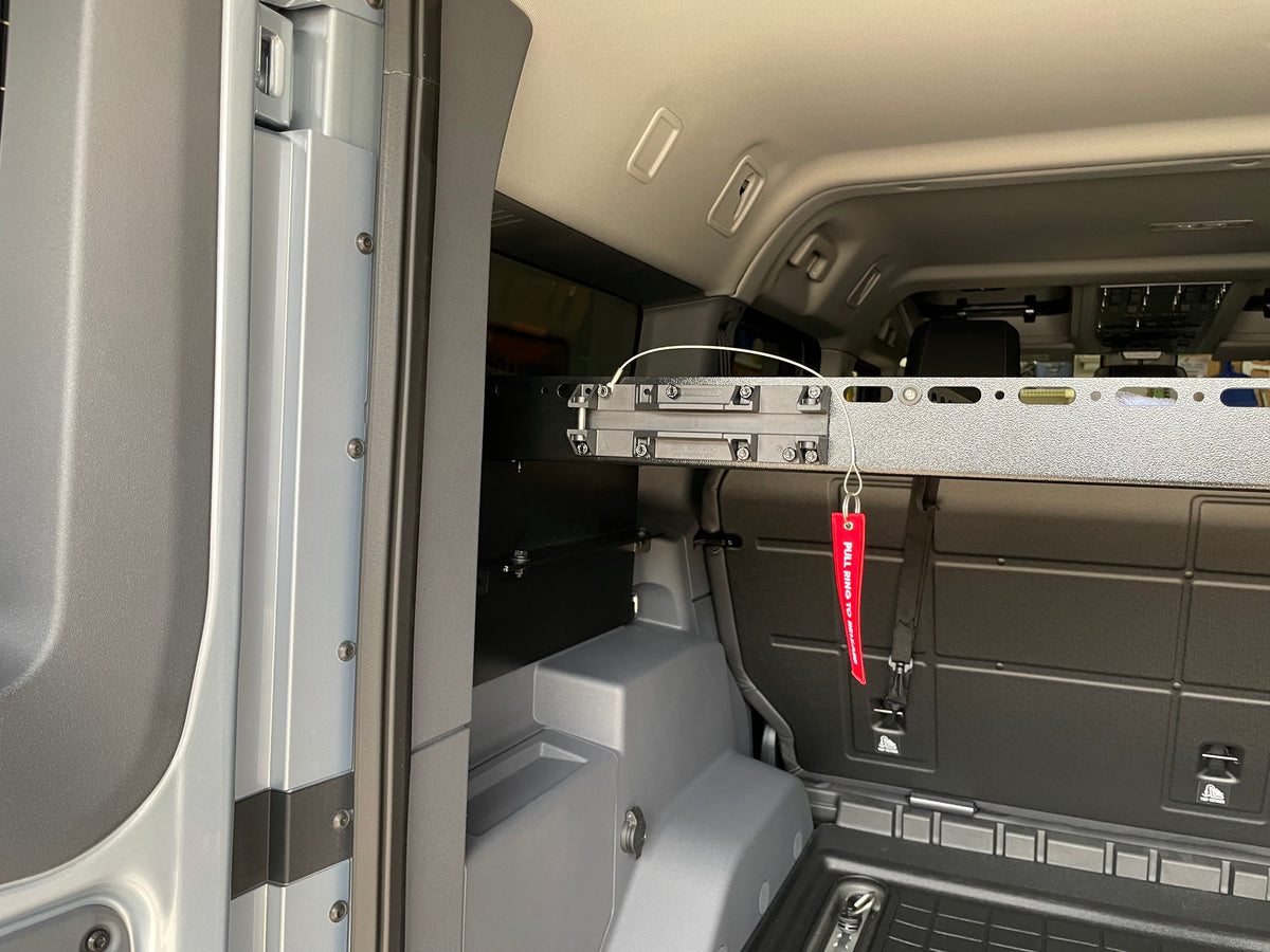 Crossbar with a red pull strap mounted behind the Grenadier rear seats