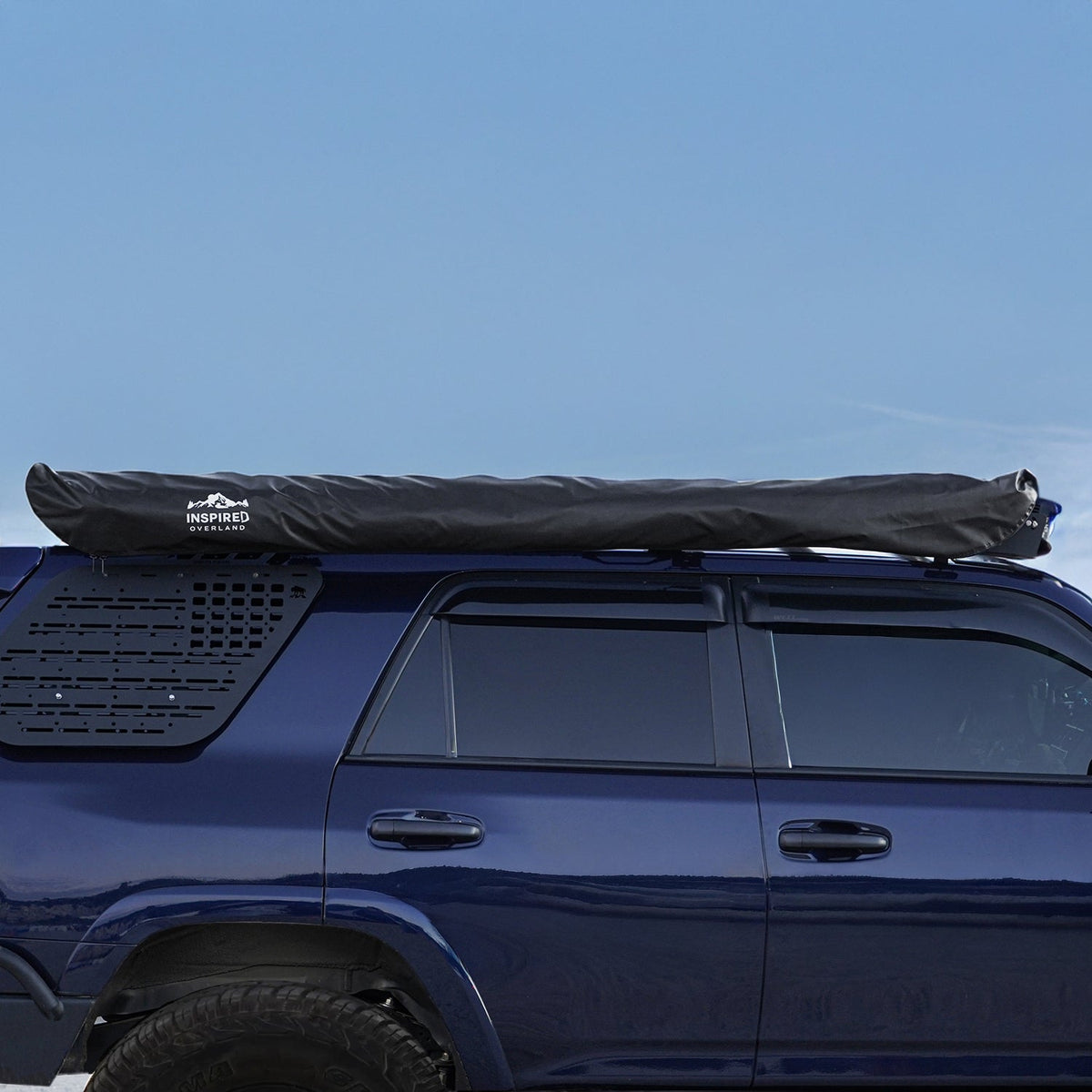 180° awning stowed in its black cover on the roof of a blue SUV