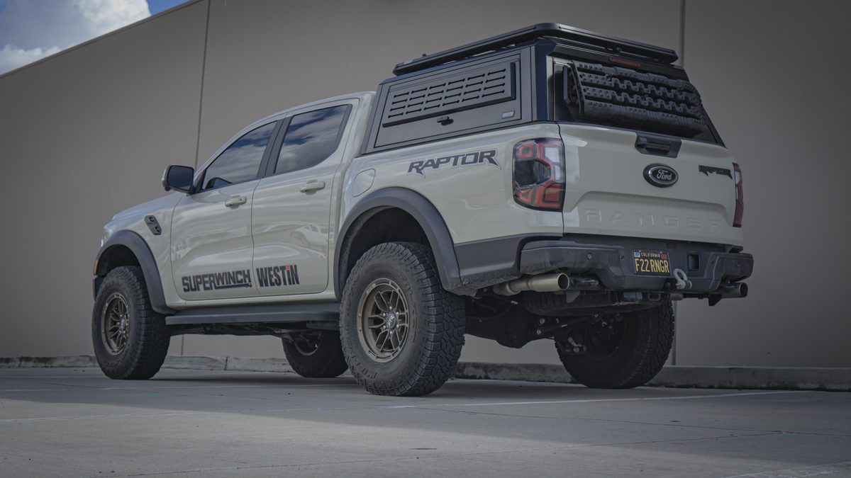 Rear three-quarter view of a 2024+ Ford Ranger Raptor with bed canopy and roof rack