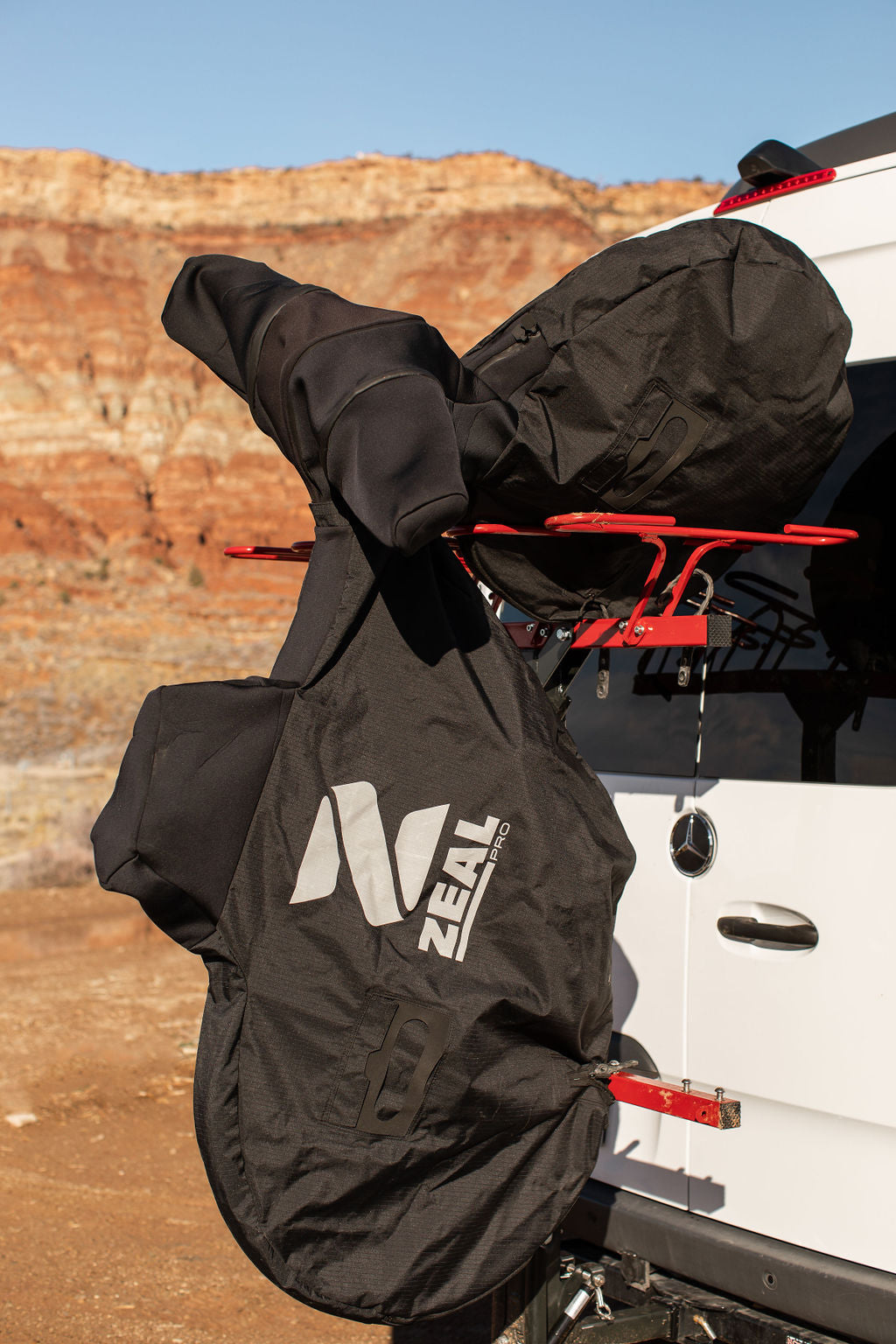 Mountain bike in a modified ZEAL Pro cover hanging on a VelociRAX rack on a Sprinter van in red-rock country