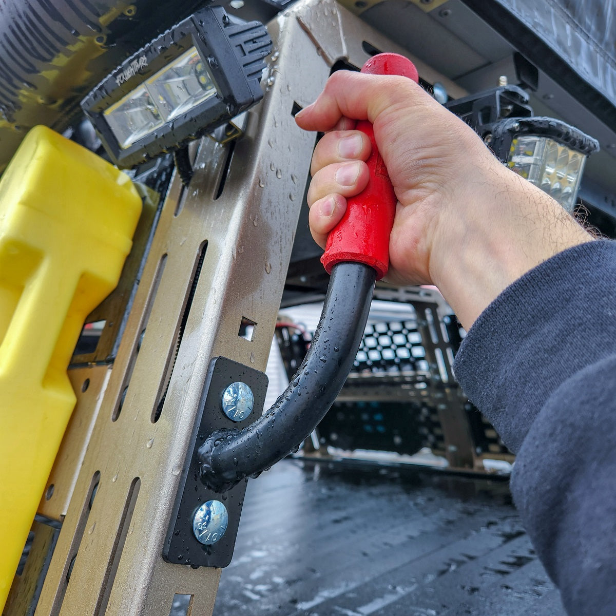 Hand gripping a red HMOR grab bar on a ROCK-IT rack panel