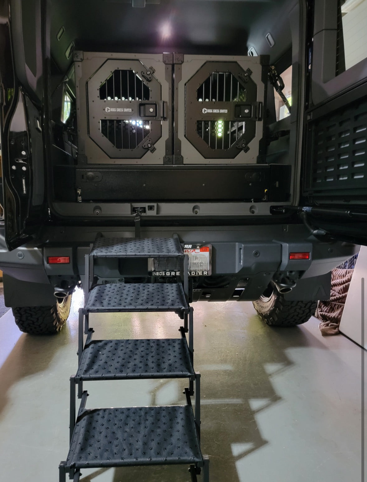 Dog crates on the drawer deck with folding steps at the rear of a Grenadier