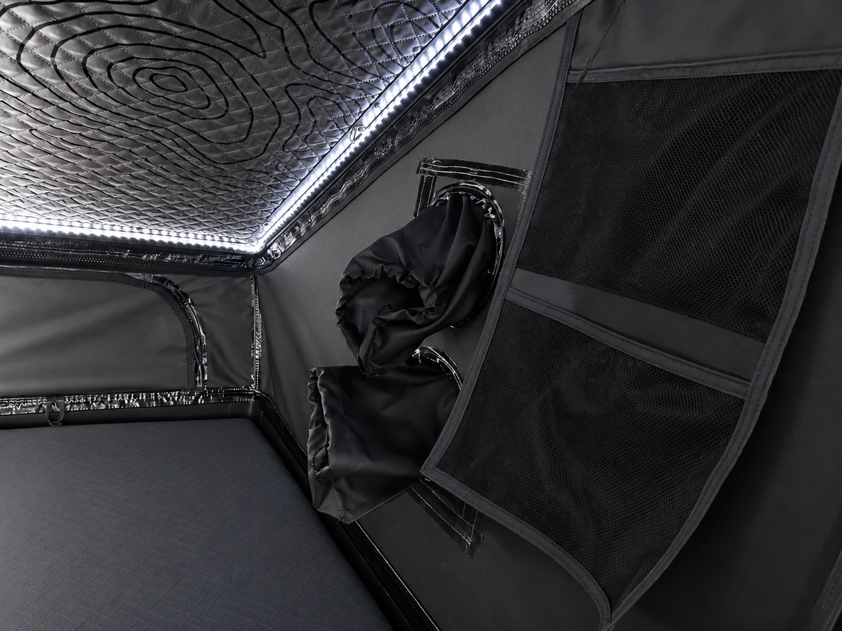 Interior close-up of storage pockets on the Dark Rogue tent wall beneath an LED-lit quilted ceiling