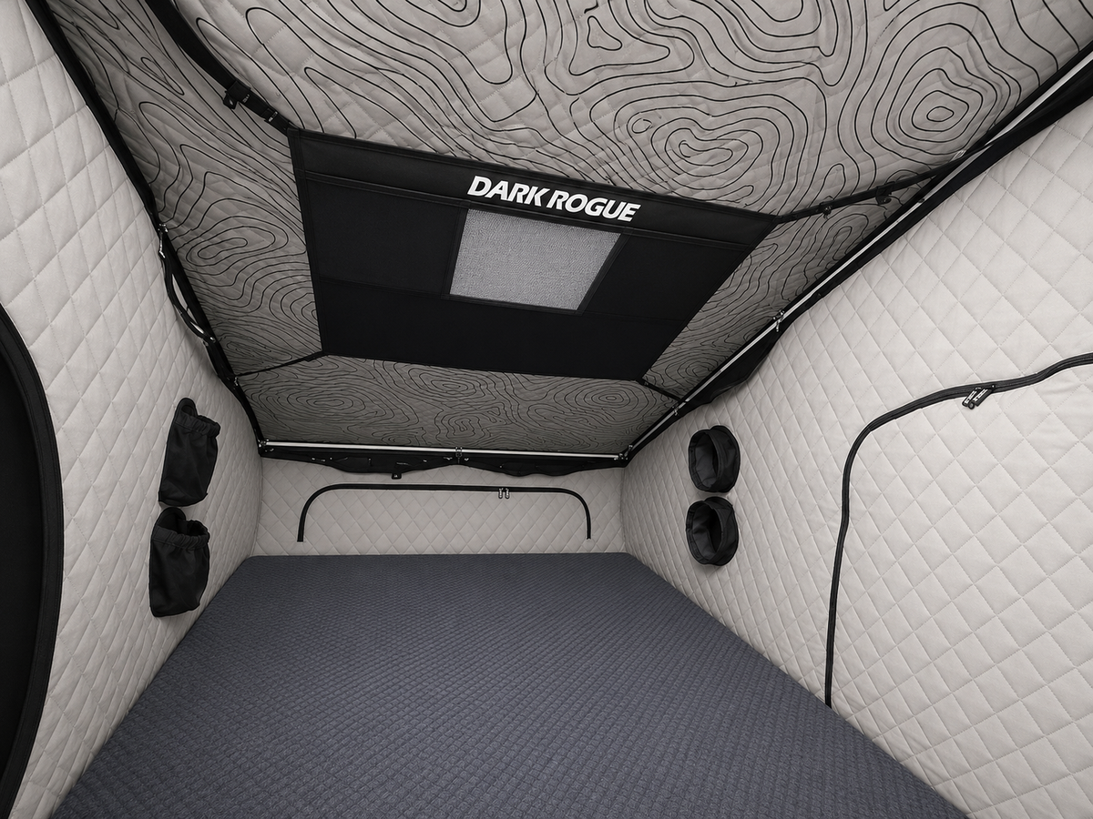 Interior of the Dark Rogue tent with light quilted walls, a topographic-print ceiling and a storage net