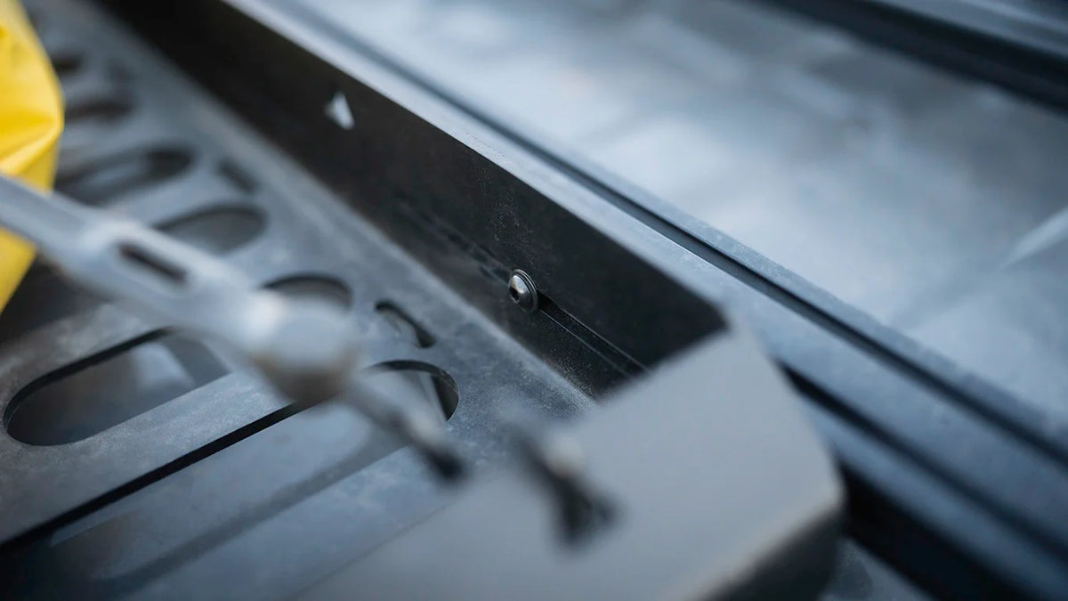 Close-up of the empty Roof Rack Storage Basket's slotted panel and tie-down straps mounted on a roof rack