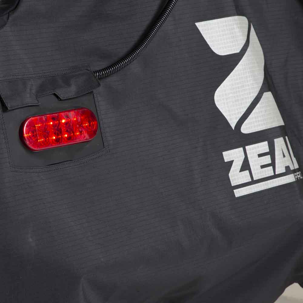 Close-up of a Light Kit LED tail light in its cover pocket next to the reflective ZEAL logo