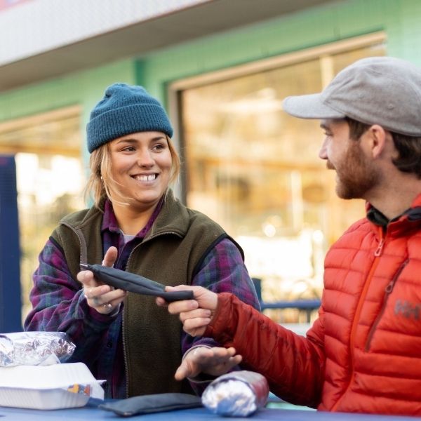 Woman and man eating together outdoors near a shop entrance
