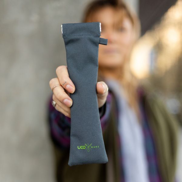 Woman holding the olive green utensil pouch with utensils tucked inside