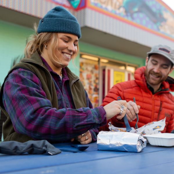 Two people talking and eating outdoors near a shop