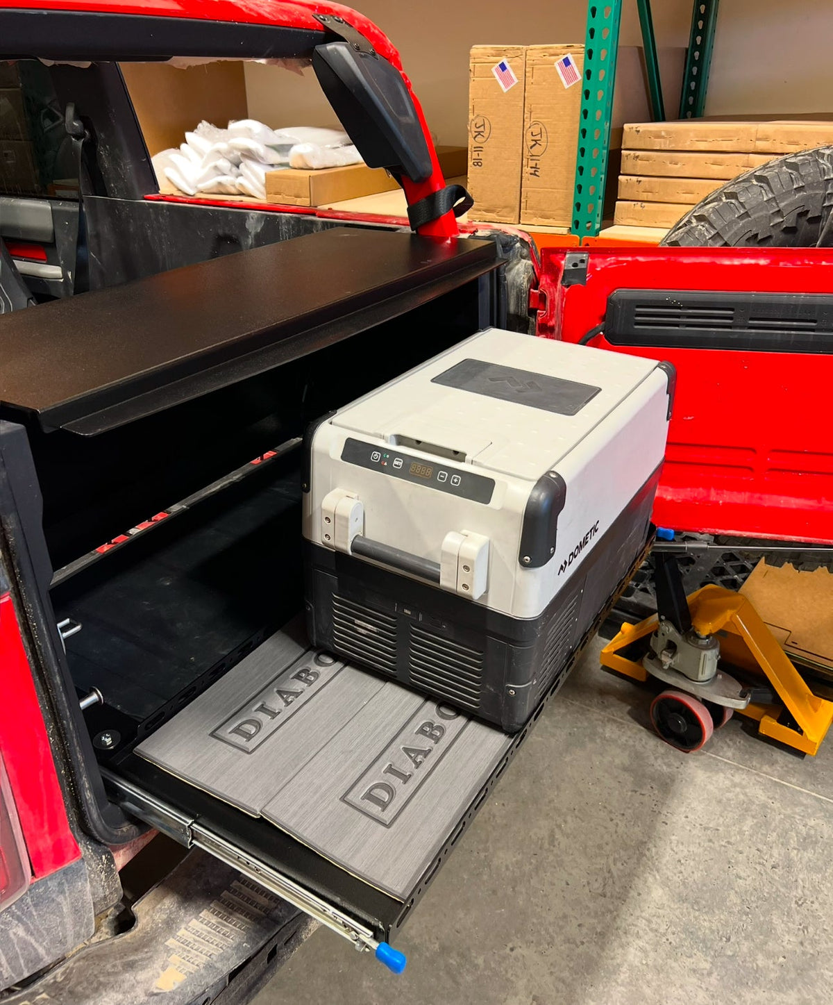 Locker slide tray extended from a red Bronco 2-door with a fridge on a Diabolical foam pad