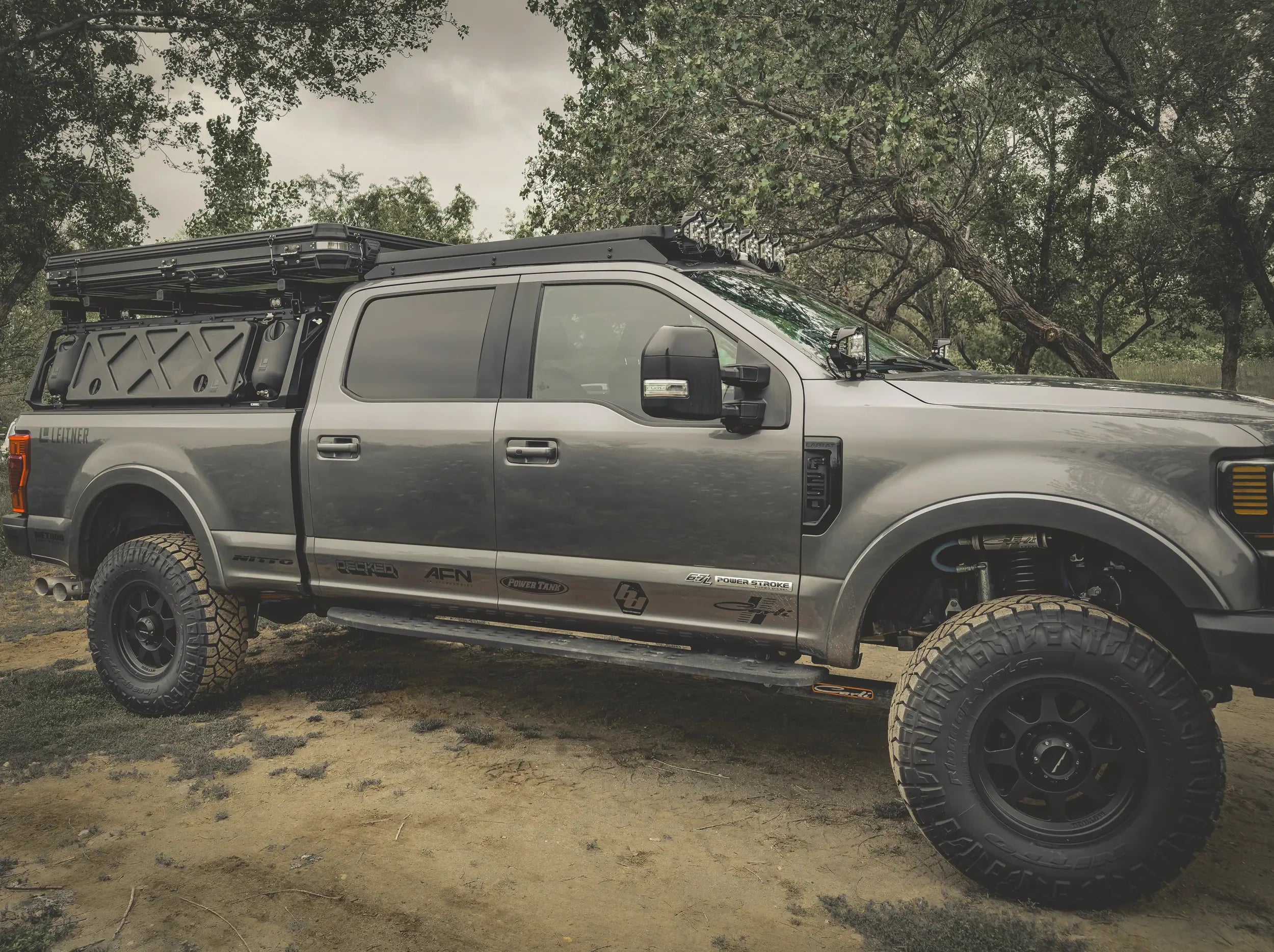 SIDE VIEW OF FORD SUPERDUTY WITH ACS ROOF RACK MOUNTED ALONG WITH ACS FORGED BED RACK AND ACCESSORIES