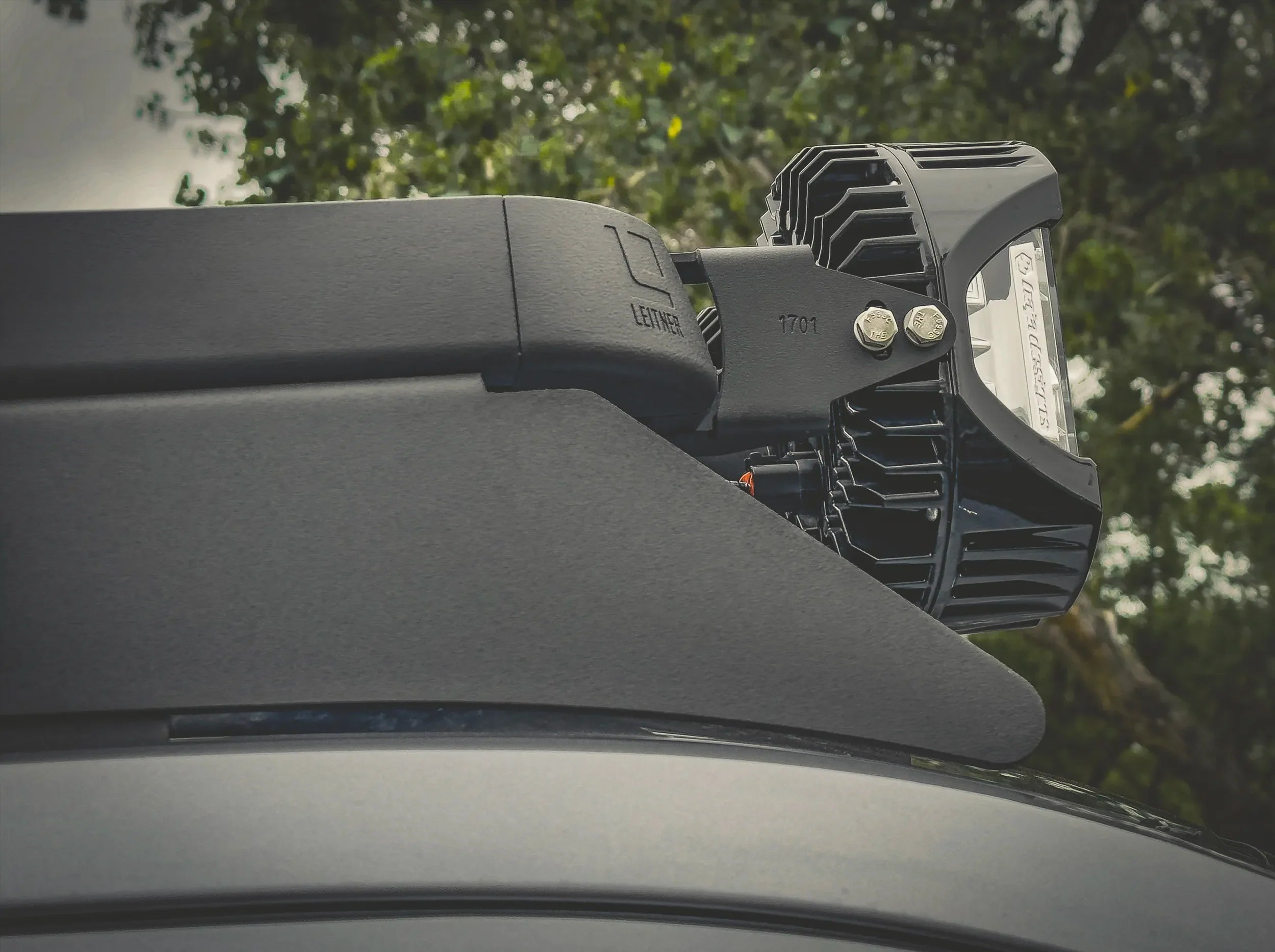 CLOSE UP SIDE VIEW OF LIGHTS ATTACHED TO ACS ROOF RACK SHOWING CORNER CAP WITH LEITNER LOGO