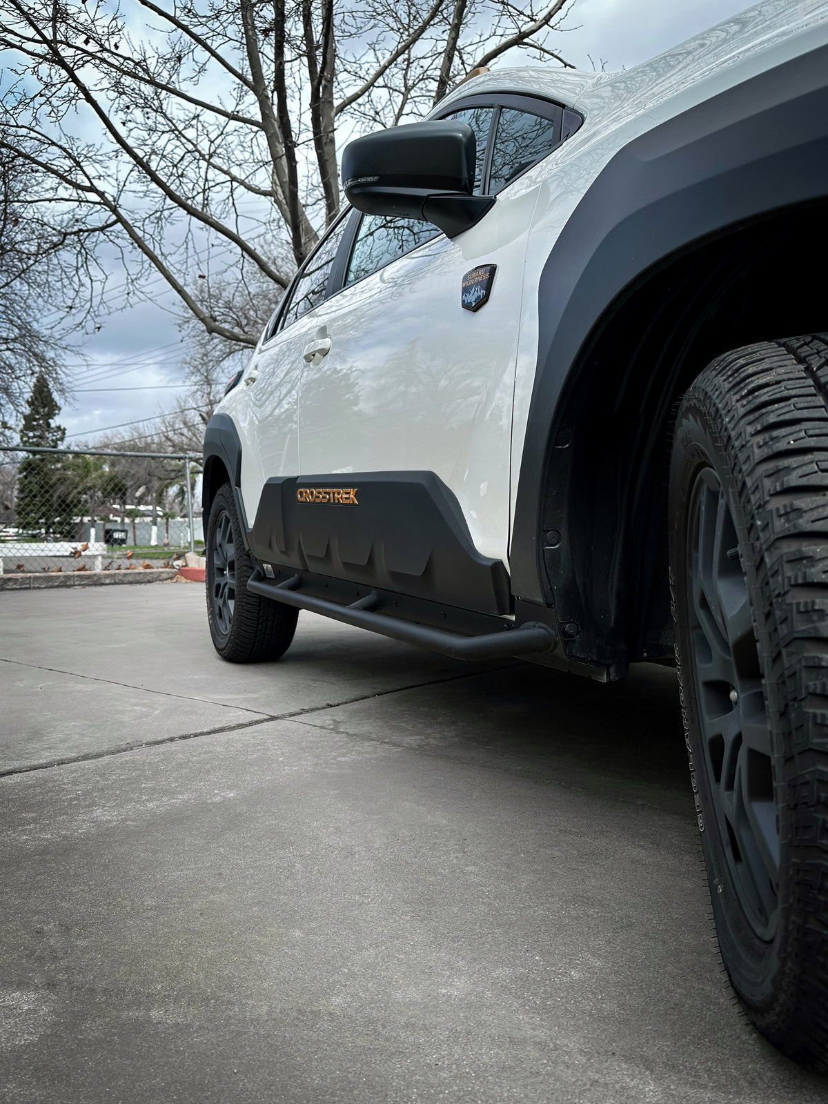 Front three-quarter view of a white SUV with rock sliders along the lower body
