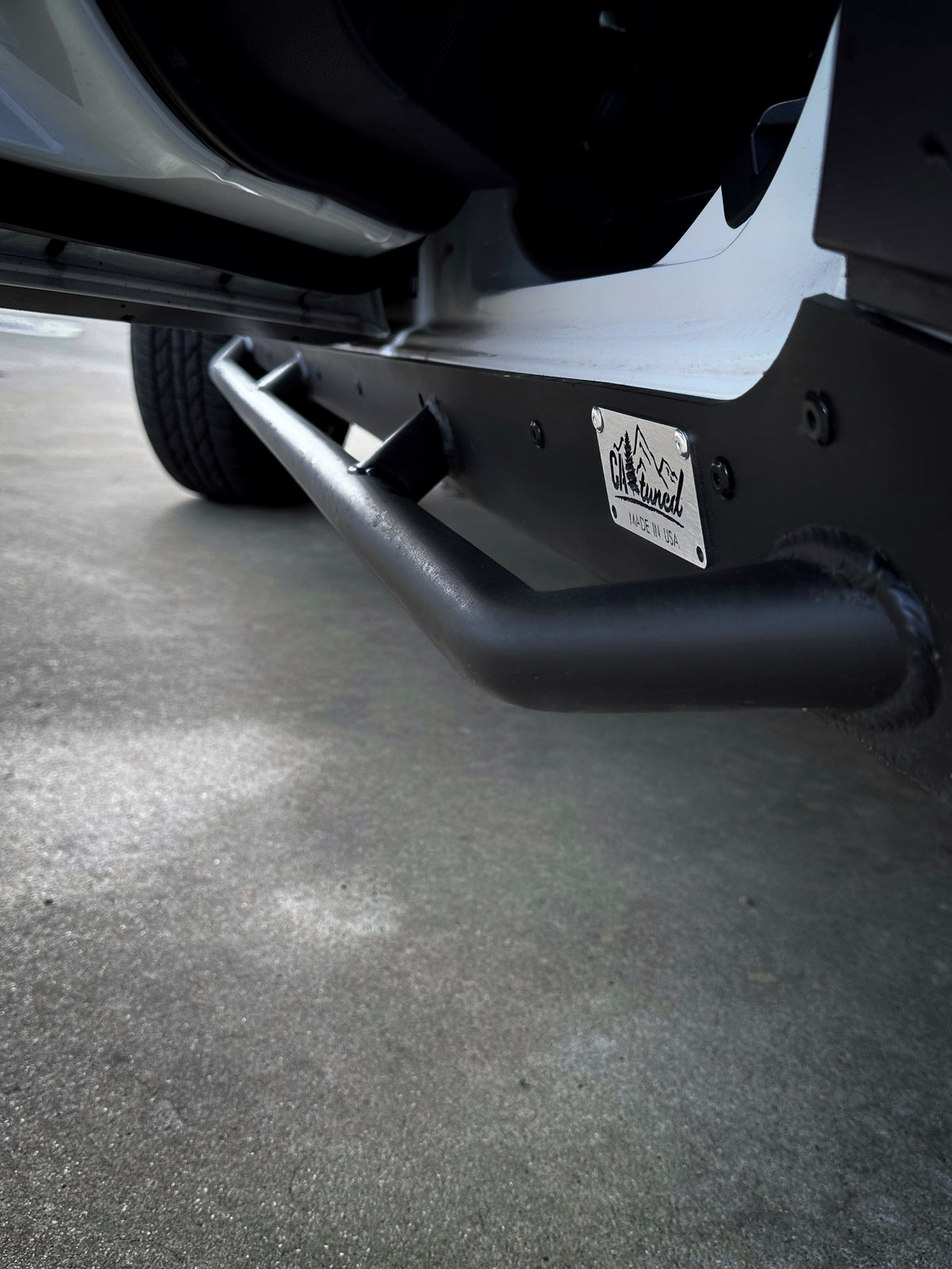 Close view of a black rock slider tube and end plate with a badge