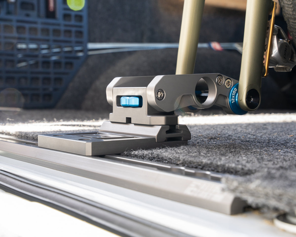 Fork mount clamped to the offset plate on an L-track rail over carpet