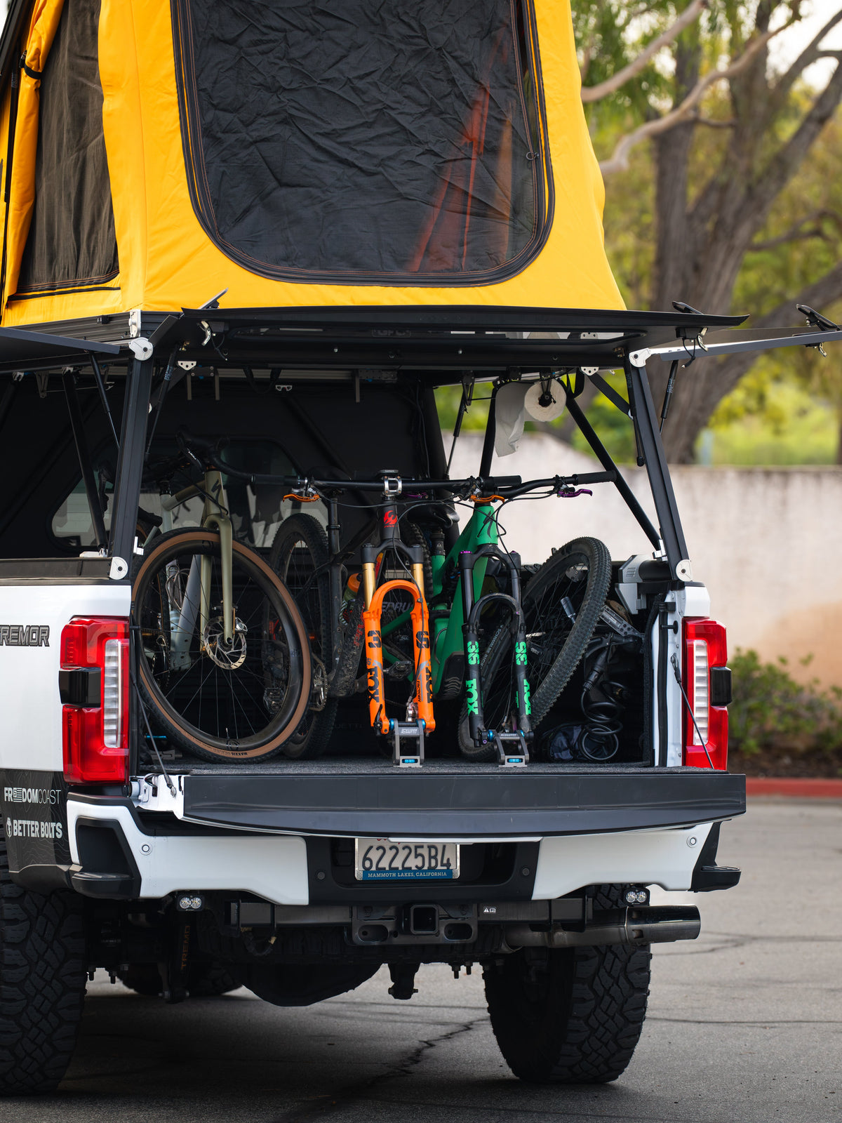 Ford truck with tailgate down showing bikes held on Freedom Track in the bed under a camper