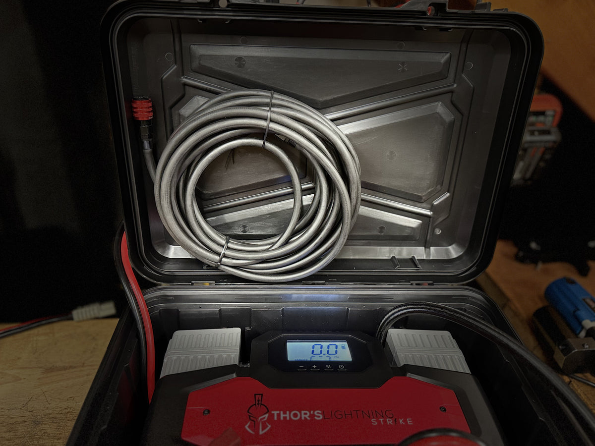 Coiled braided air hose stored in the lid compartment of the AirVault StrikePro's hard case