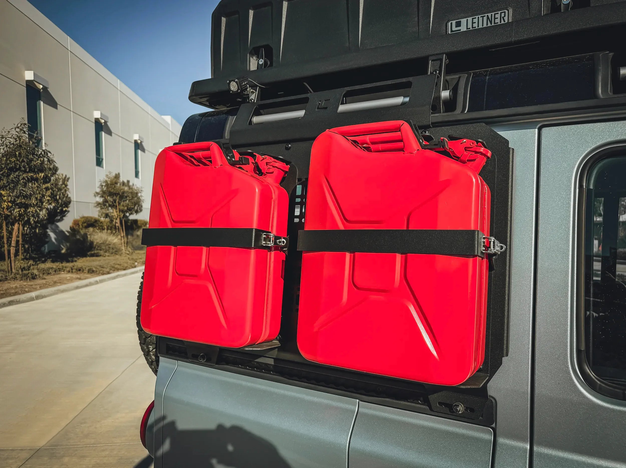 CLOSE UP VIEW OF TWO JERRY CANS HELD UP ON TWO JERRY CAN HOLDERS MOUNTED ON SIDEKICK PANEL FOR INEOS GRENADIER