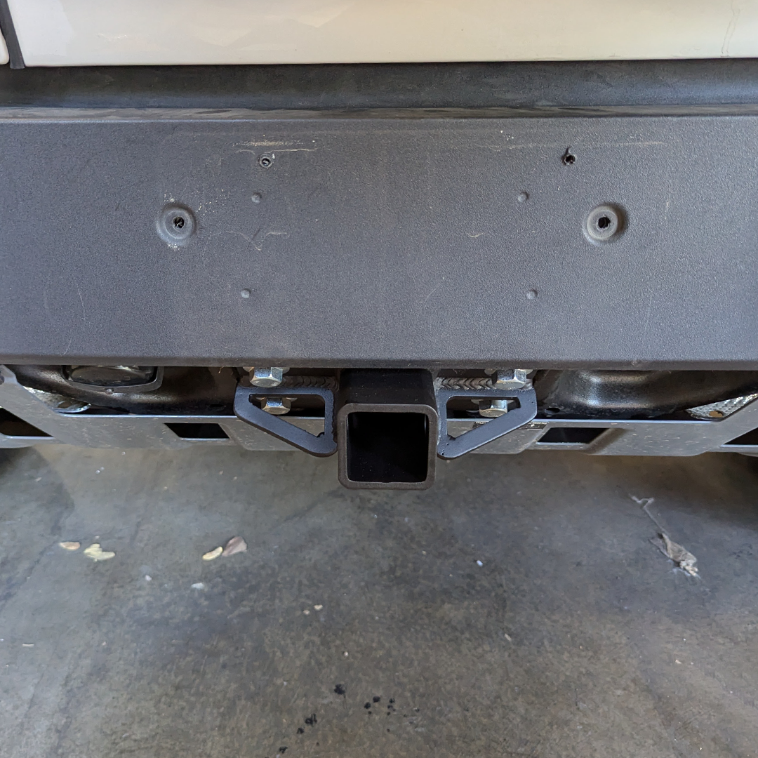 Hitch receiver mounted under the rear bumper of a gray vehicle