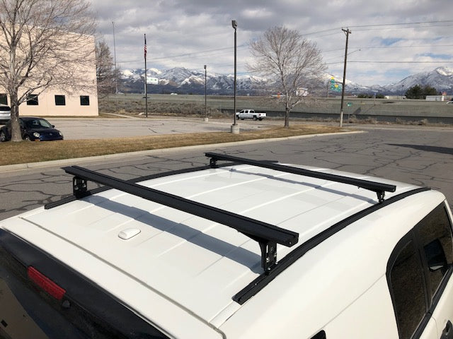 Eezi-Awn K9 load bars on a white vehicle roof, side view