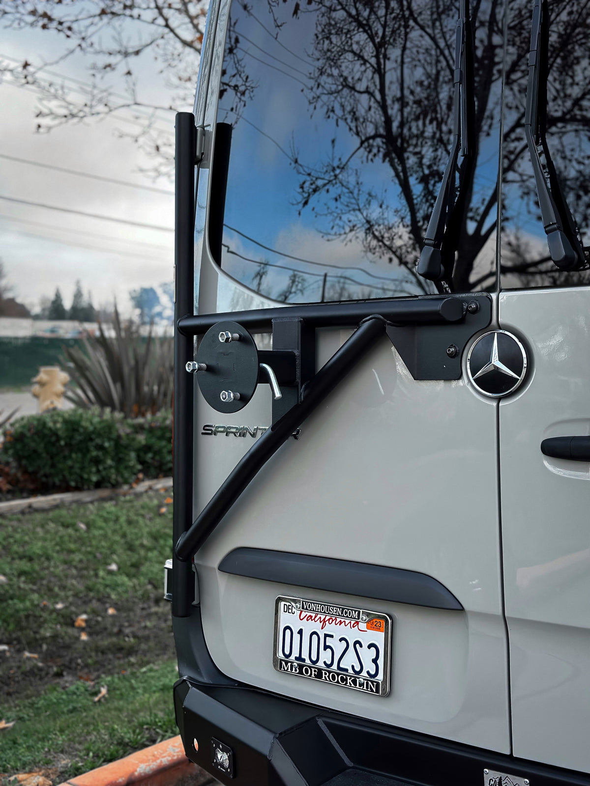 Spare tire carrier mounted on the rear door of a gray van