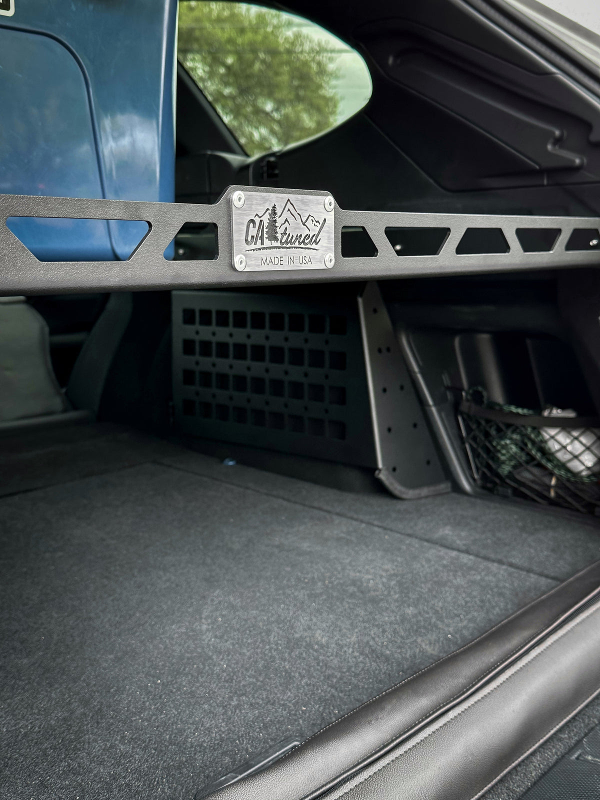 Metal-framed cargo shelf with a plate in the back of a wagon, carpeted floor below