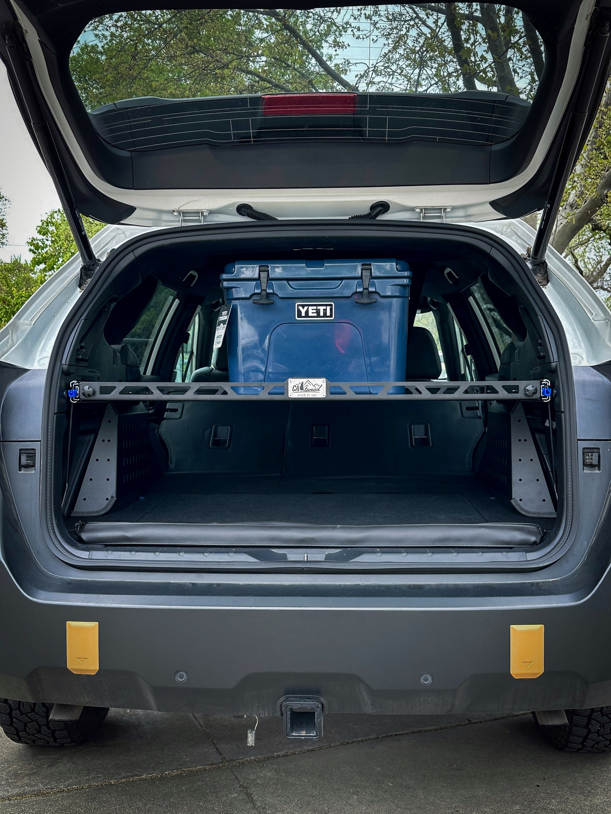 Open rear hatch of a Subaru wagon with a cargo shelf holding a blue cooler