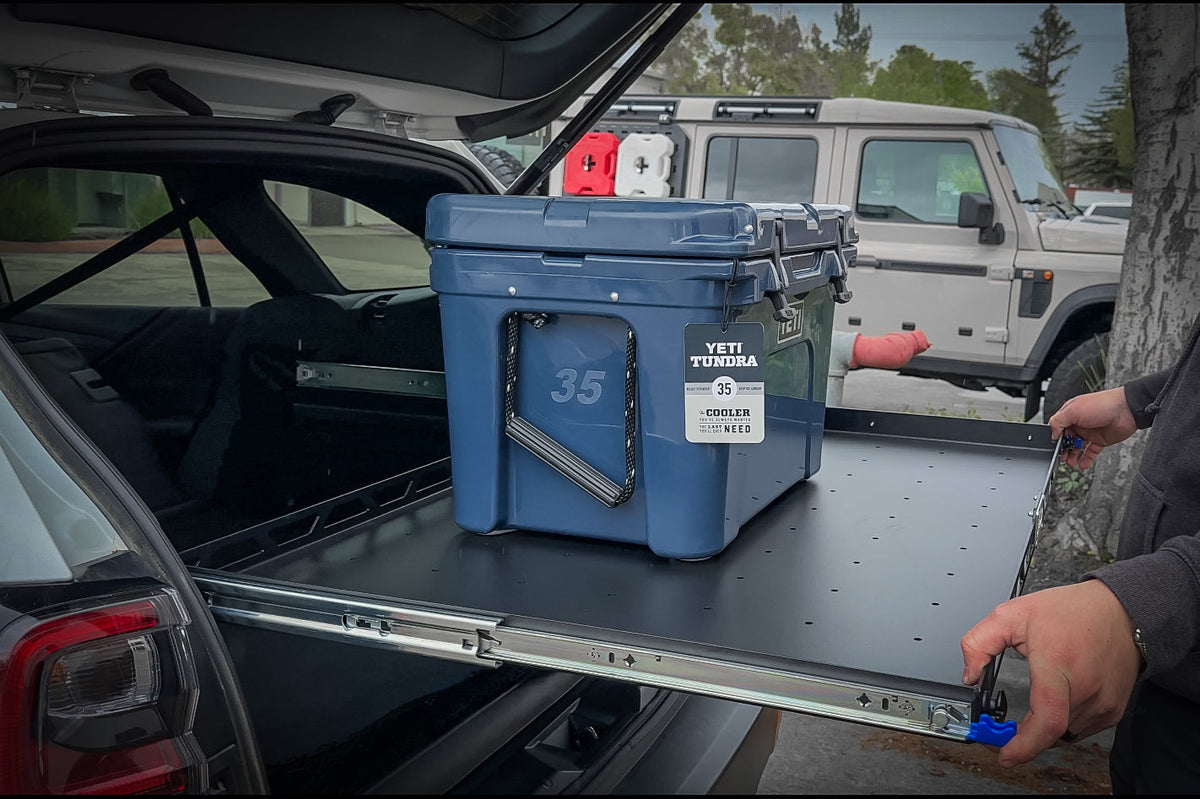 Hand pulling out the sliding shelf with a blue cooler on it