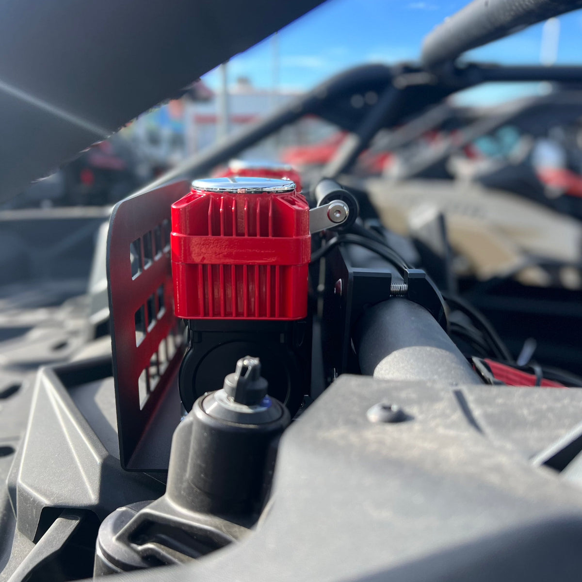 Close-up of a red 12V compressor secured in the Refuge MOLLE mount on a side-by-side's rollbar