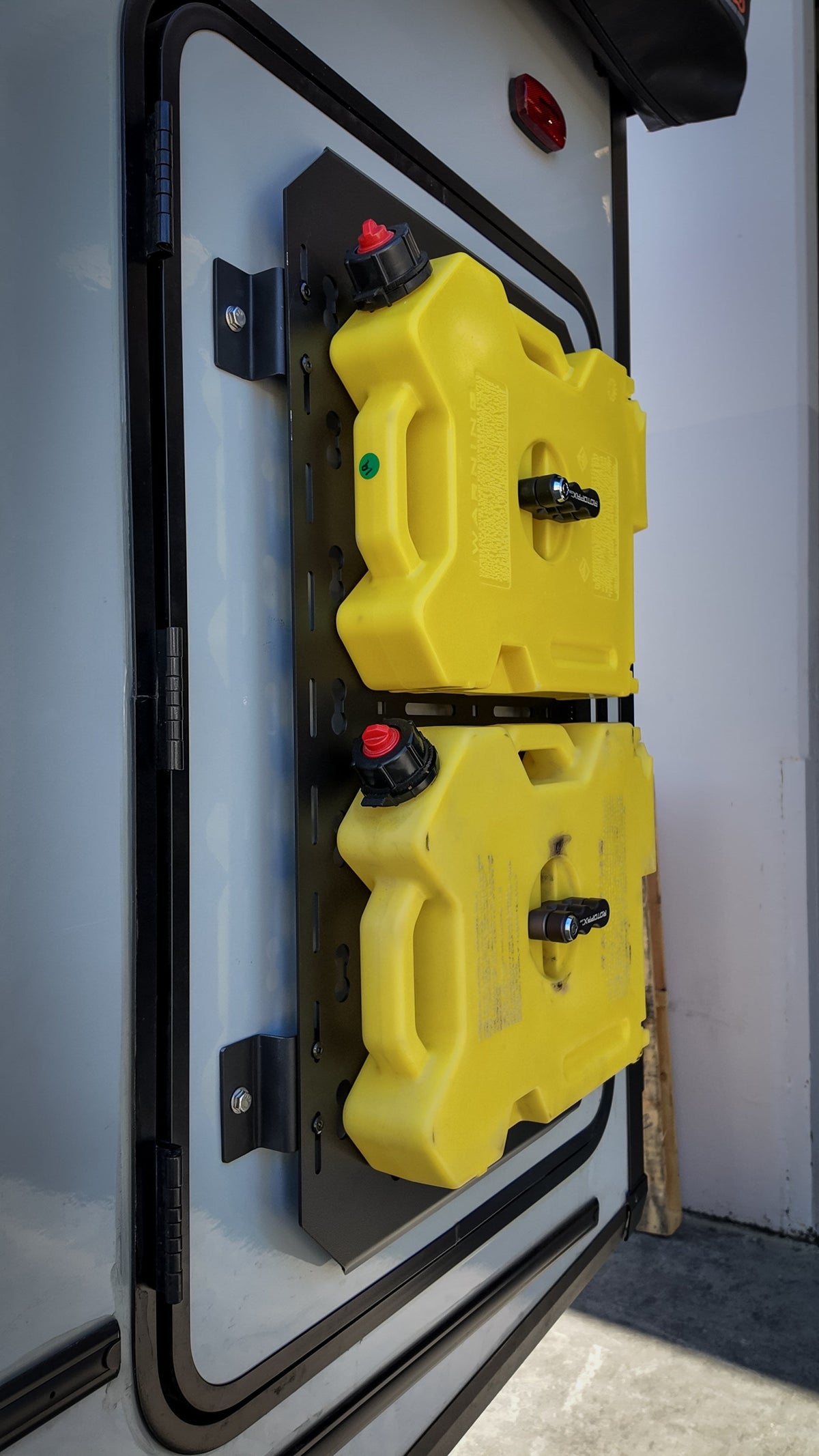 Two yellow fuel cans mounted vertically on a MOLLE panel
