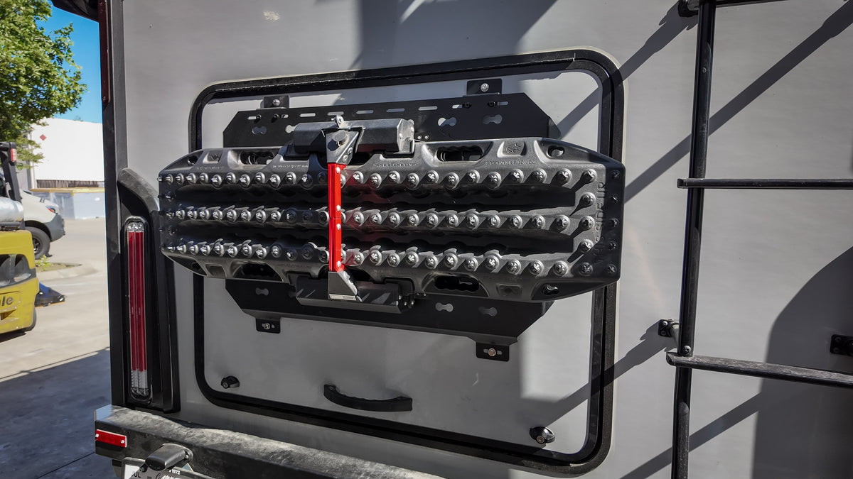 Recovery boards with a red strap on a MOLLE panel on a van door