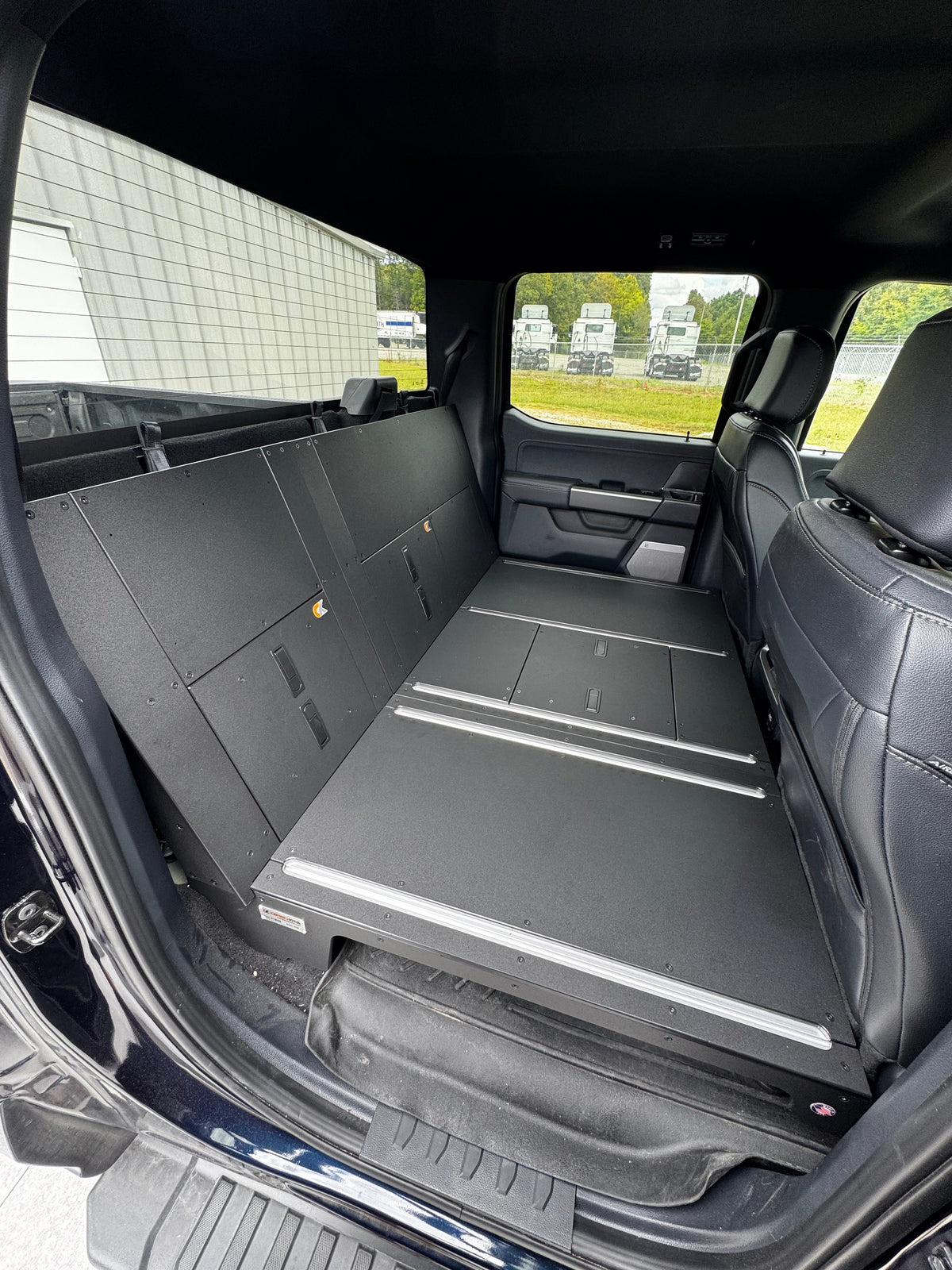 CargoKits Rear Seat Delete installed in a Ford F-Series SuperCrew, wide interior shot showing the flat storage platform and MOLLE side panel