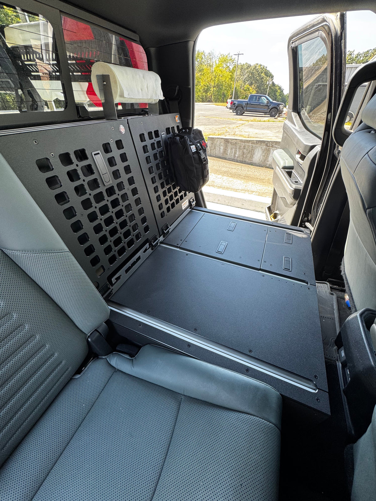 CargoKits seat delete platform in a crew cab truck, with the perforated MOLLE rear panel, first-aid pouch, paper towel roll, and top hatches visible