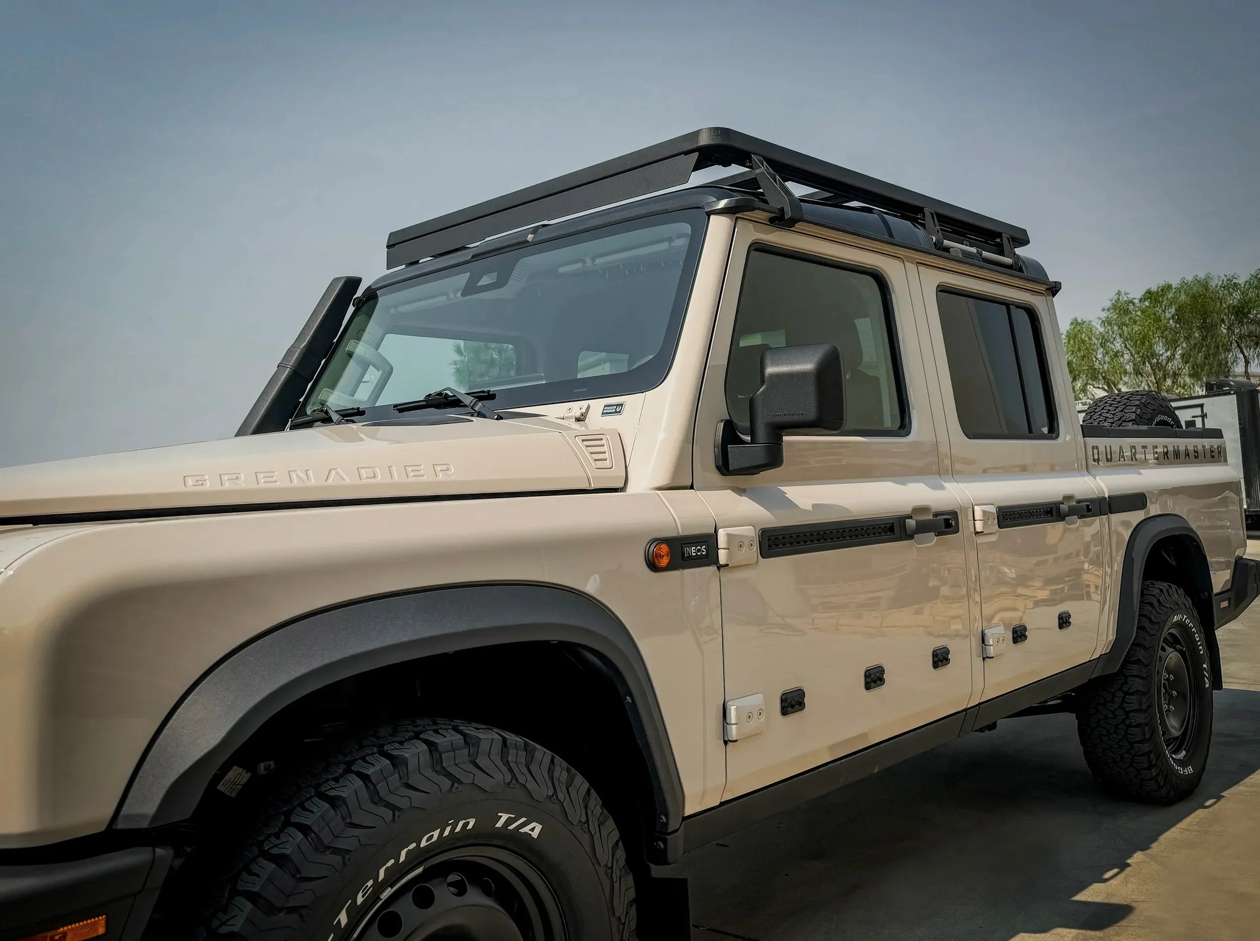 SIDE VIEW OF TAN GRENADIER QUARTERMASTER TURCK WITH FULL LENGTH ACS ROOF RACK