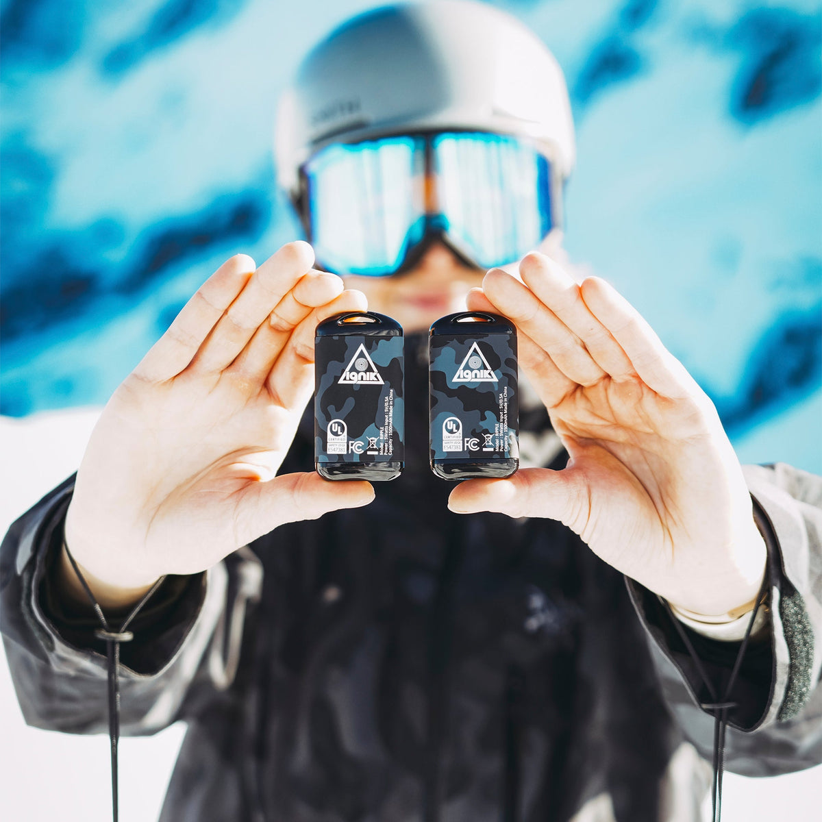 Skier in a helmet and goggles holding a pair of Ignik Ripple hand warmers