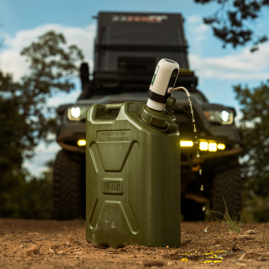 Olive-green military water can with the Lone Rock Concepts pump dispensing water and an overland truck behind