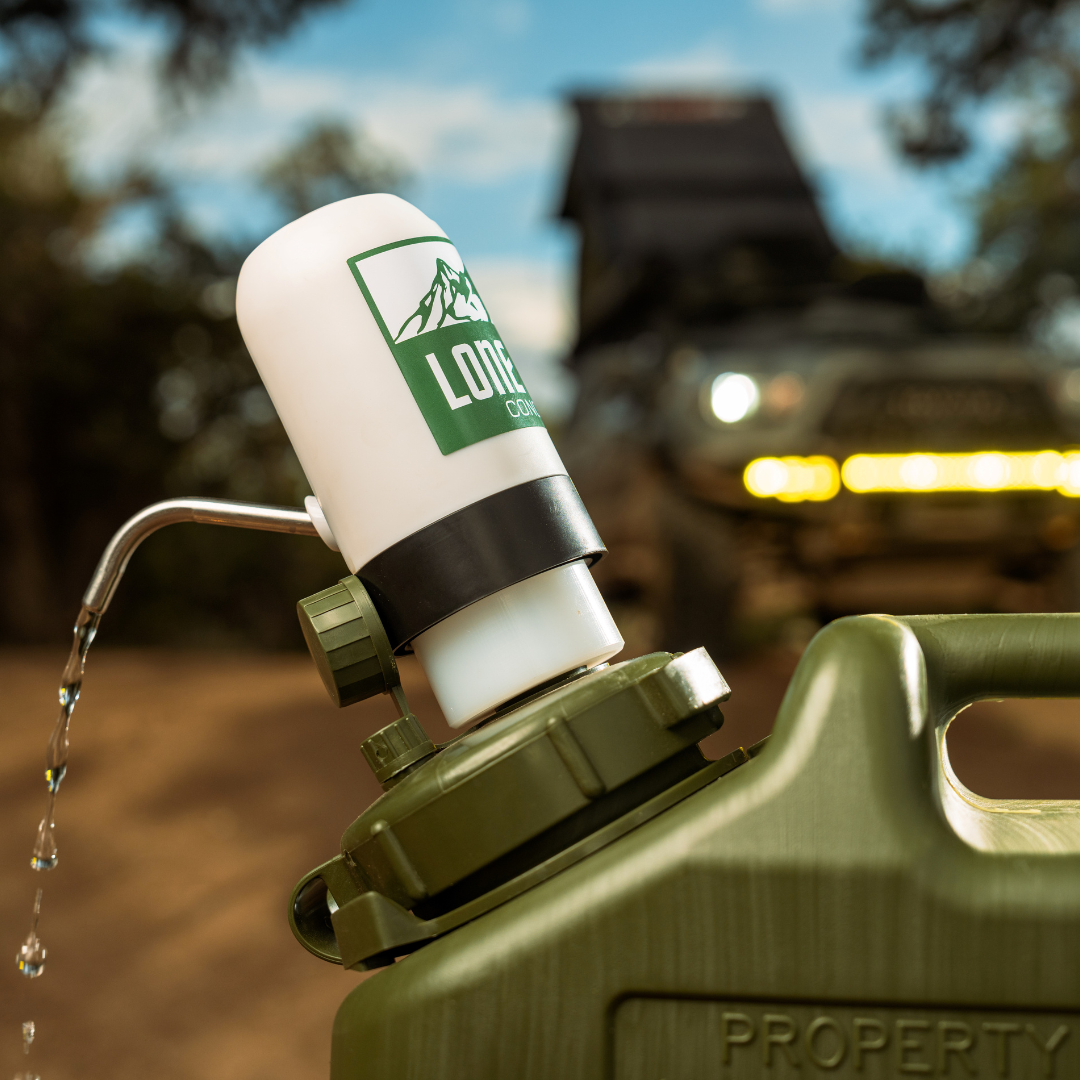 Lone Rock Concepts water pump dispensing water from an olive military can with an overland rig on the trail behind