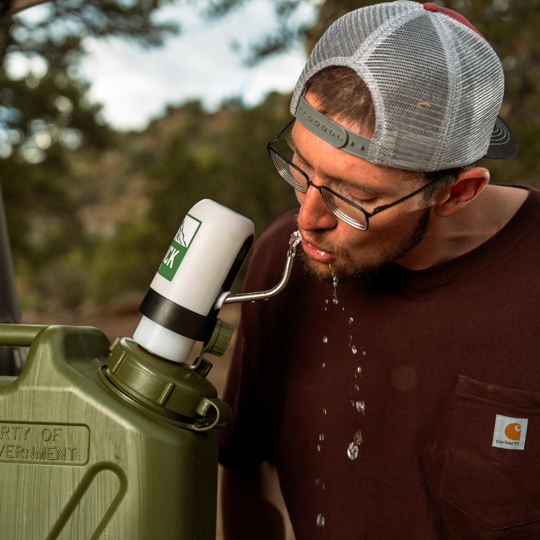 Man drinking from the Lone Rock Concepts water pump spout on an olive-green military water can