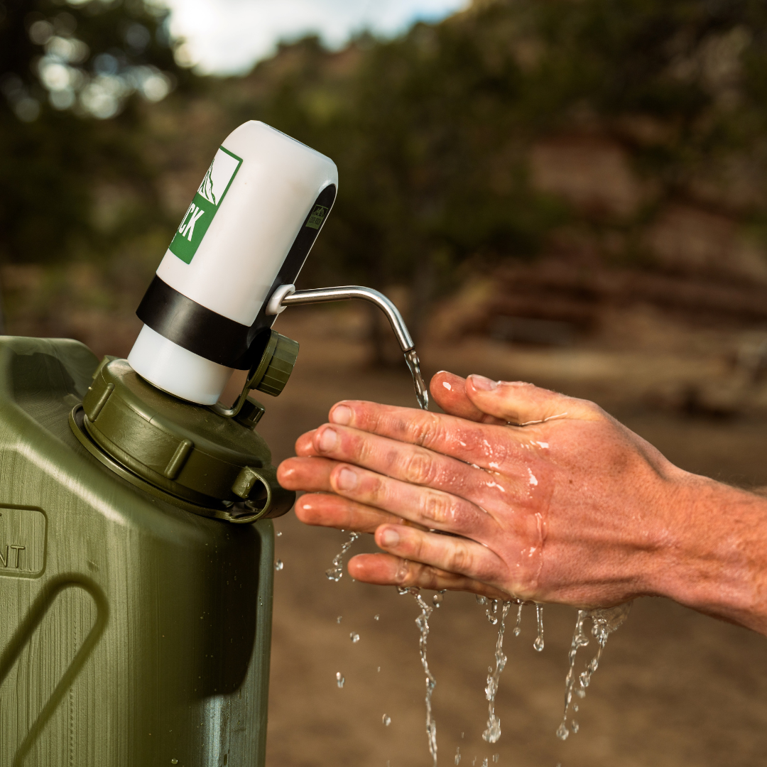 Lone Rock Concepts water pump rinsing a person's hands from an olive military water can in the desert