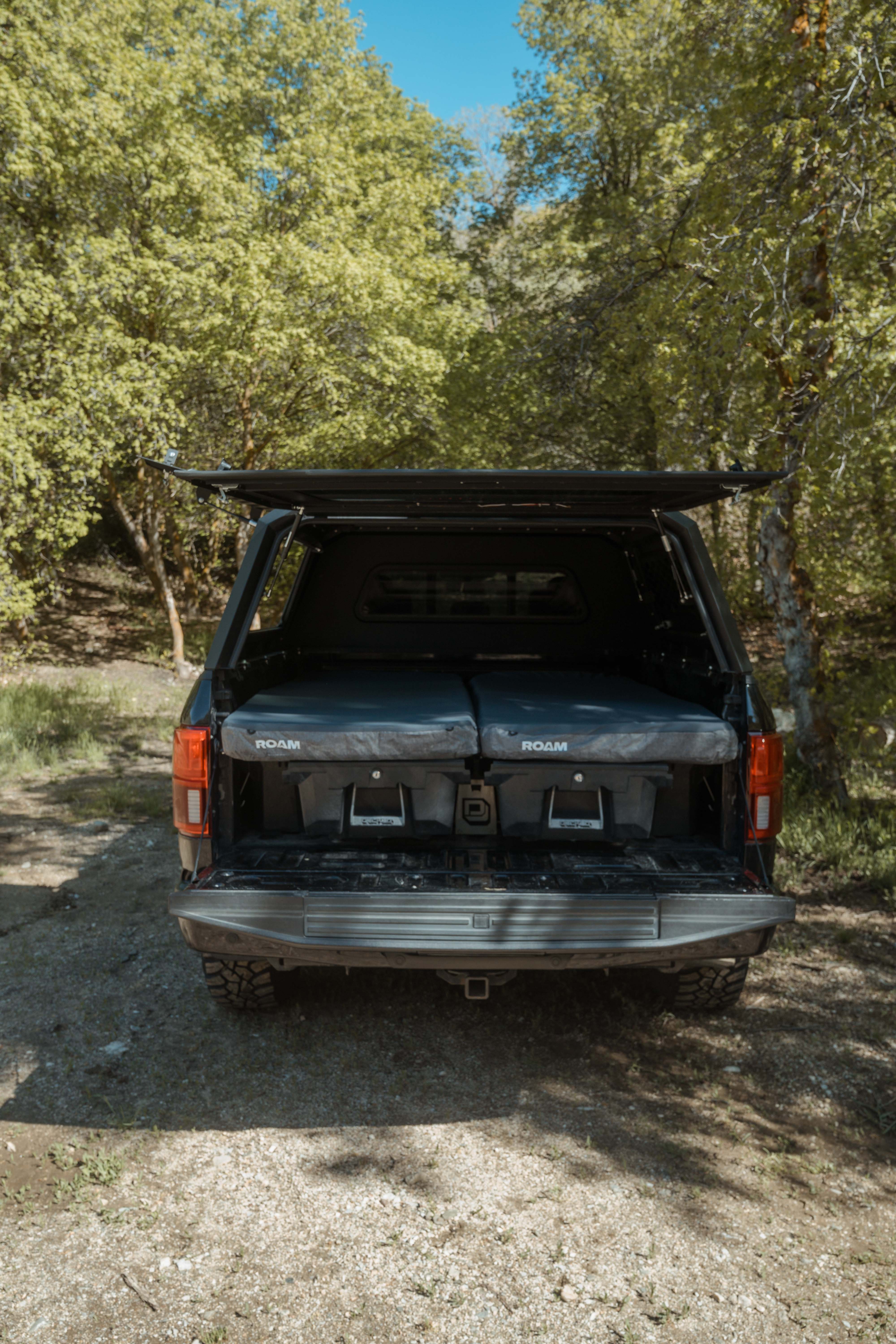 Back of a black SUV with an open cargo area in a forest setting