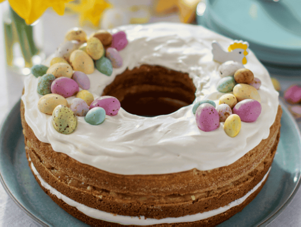 Easter-themed cake with colorful eggs and a chicken decoration on a blue plate.