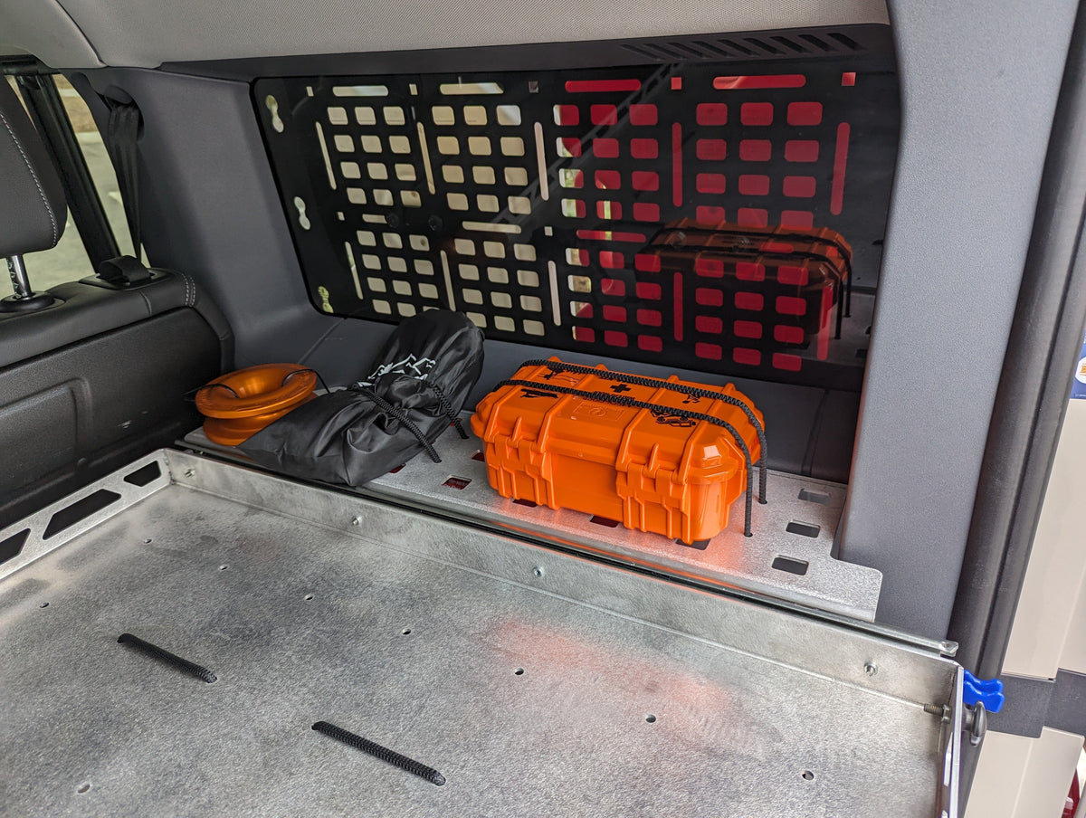 Shelf surface with an orange hard case on it and a MOLLE panel behind