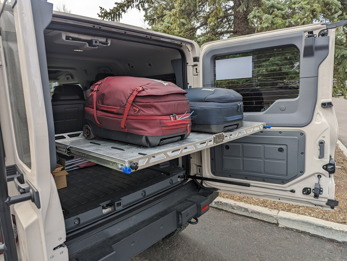 Open rear door showing the shelf above red and blue bags