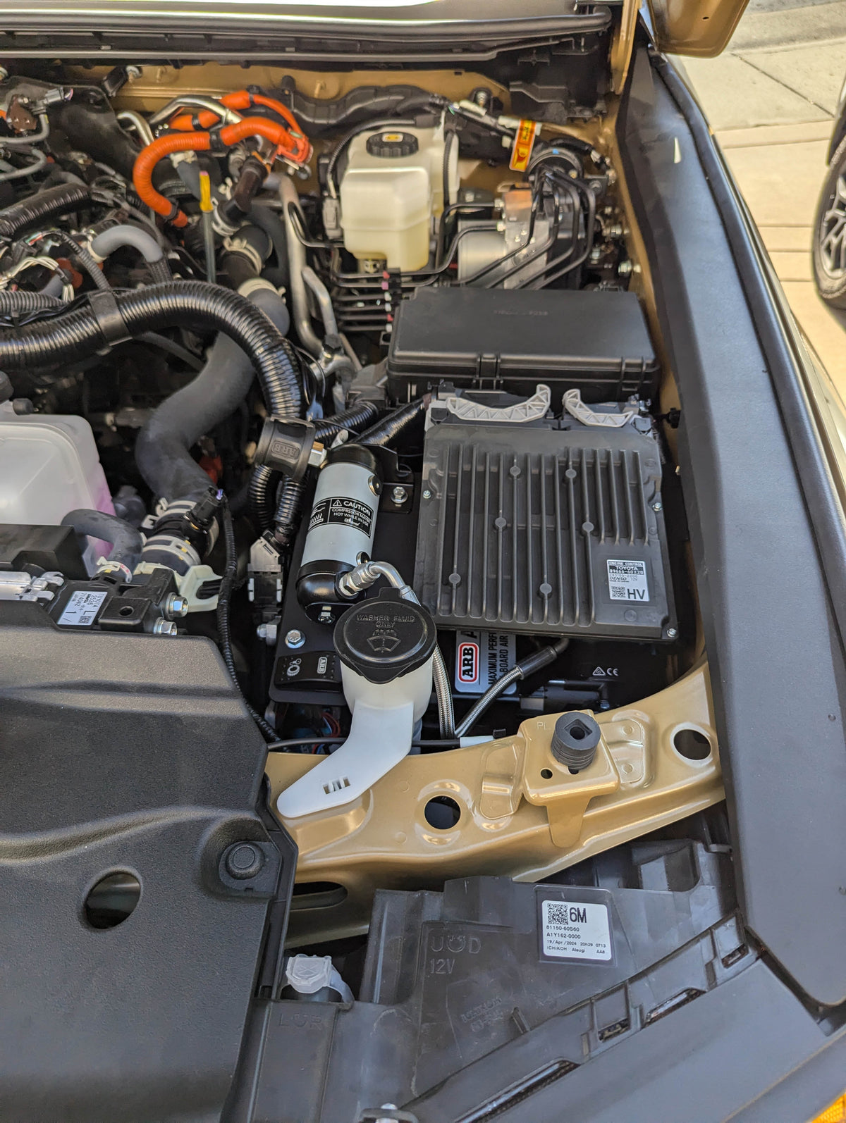 Compressor installed in a truck engine bay beside a fluid reservoir