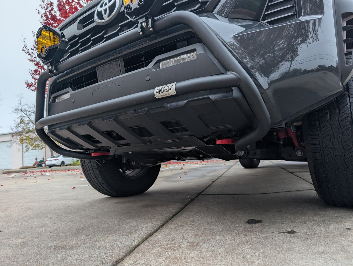 Low front view of a black brush bar below the grille of a gray Toyota truck