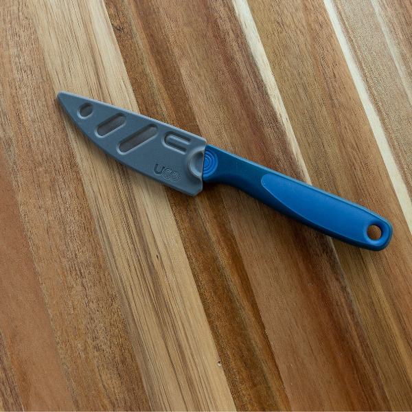 UCO Camp Paring Knife and its sheath side by side on a wood cutting board, alternate angle