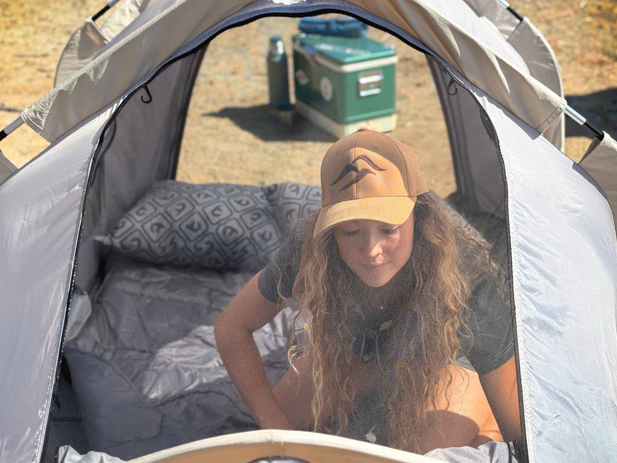 C6 Rev Pickup Truck Tent – person at a ground tent doorway on bedding