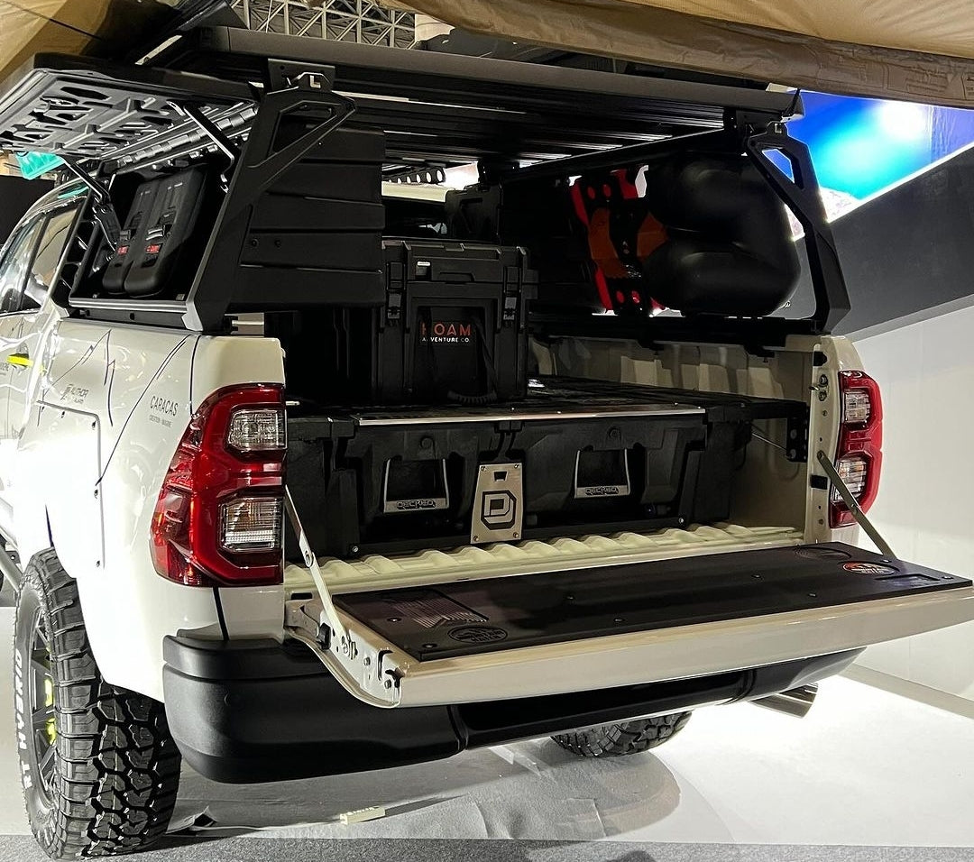 2015-2023 Toyota Hilux with a bed canopy and drawer system, Mountain Hatch tailgate table on the lowered tailgate at a show
