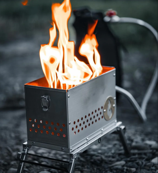 Close-up of a firebox burning with tall visible flames on folding legs outdoors